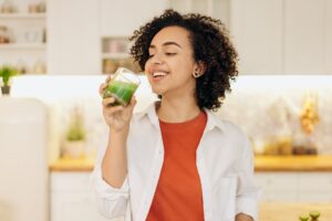 woman in white blazer drinking a fresh smoothie